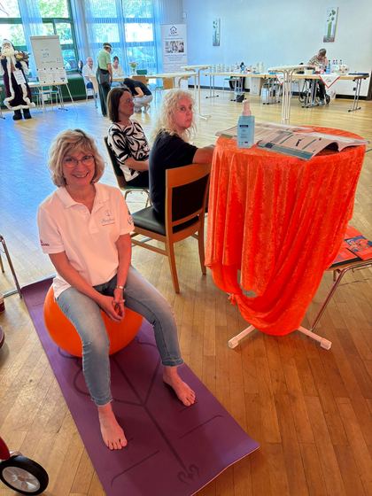Bewegungsangebot im Foyer. Eine Mitarbeiterin sitzt barfuß auf einem orangefarbenen Gymnastikball. 4. Erzhäuser Gesundheits- & Pflegetag Erzhausen 2026.