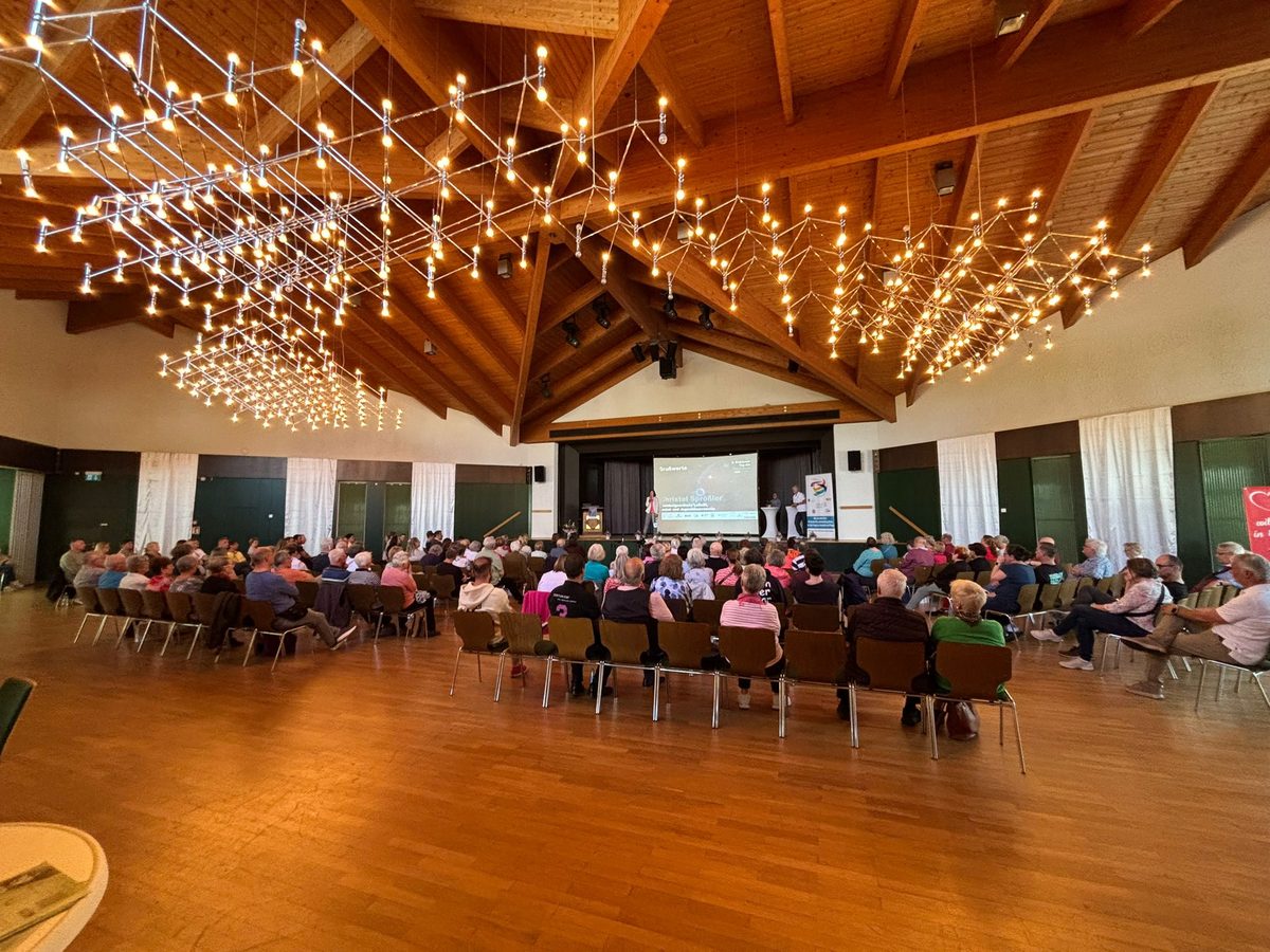 Blick in den vollen Saal des Bürgerhauses Erzhausen. Rund hundert Besucherinnen und Besucher sitzen in Stuhlreihen und schauen zur Bühne. Über ihnen der Lichterhimmel aus vielen kleinen Lampen unter dem Holzdach. 4. Erzhäuser Gesundheits- & Pflegetag Erzhausen 2026.